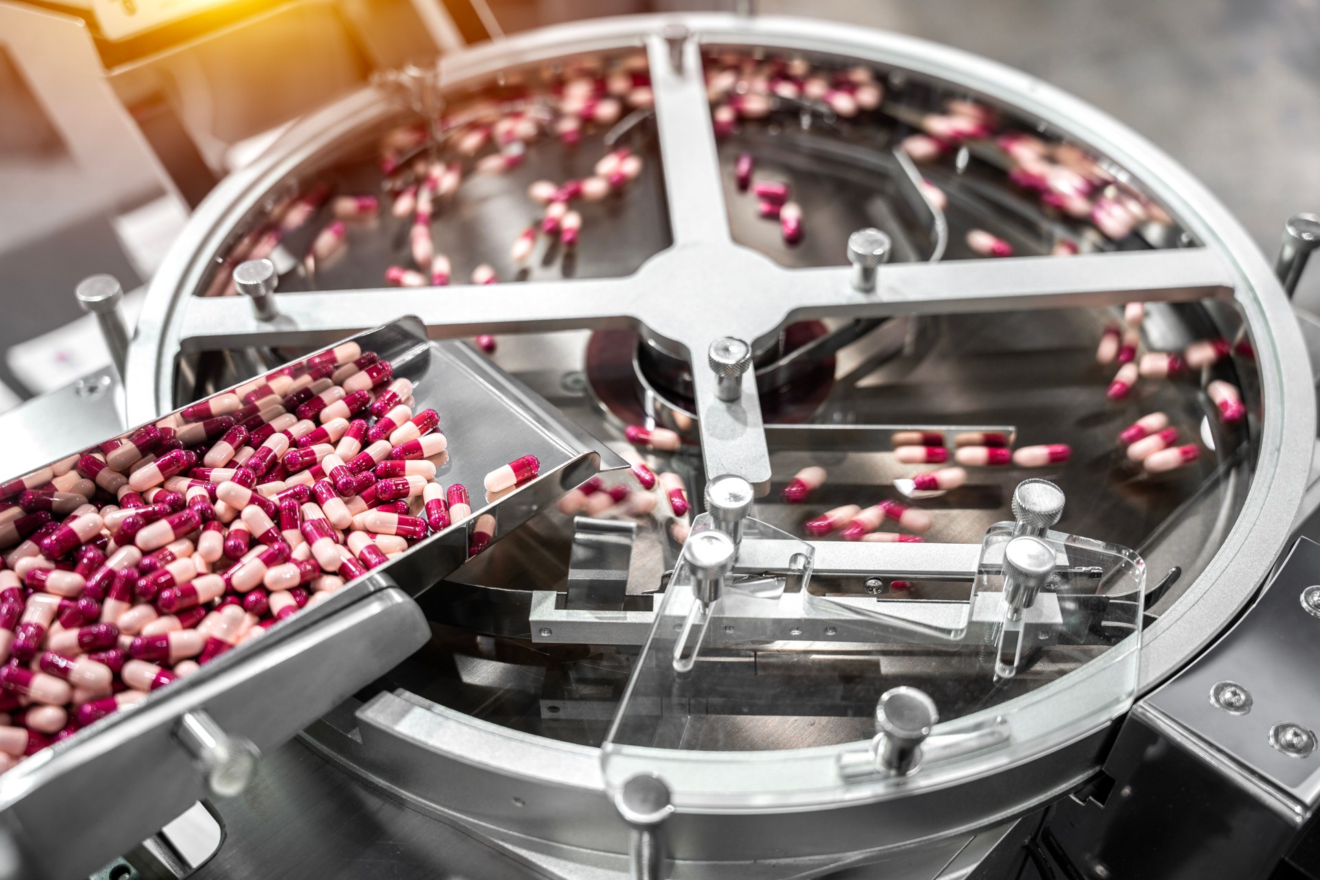 Pink and white capsules pills in the pills packaging machine, pharmacy medicine capsule pill in production line at medical factory.
